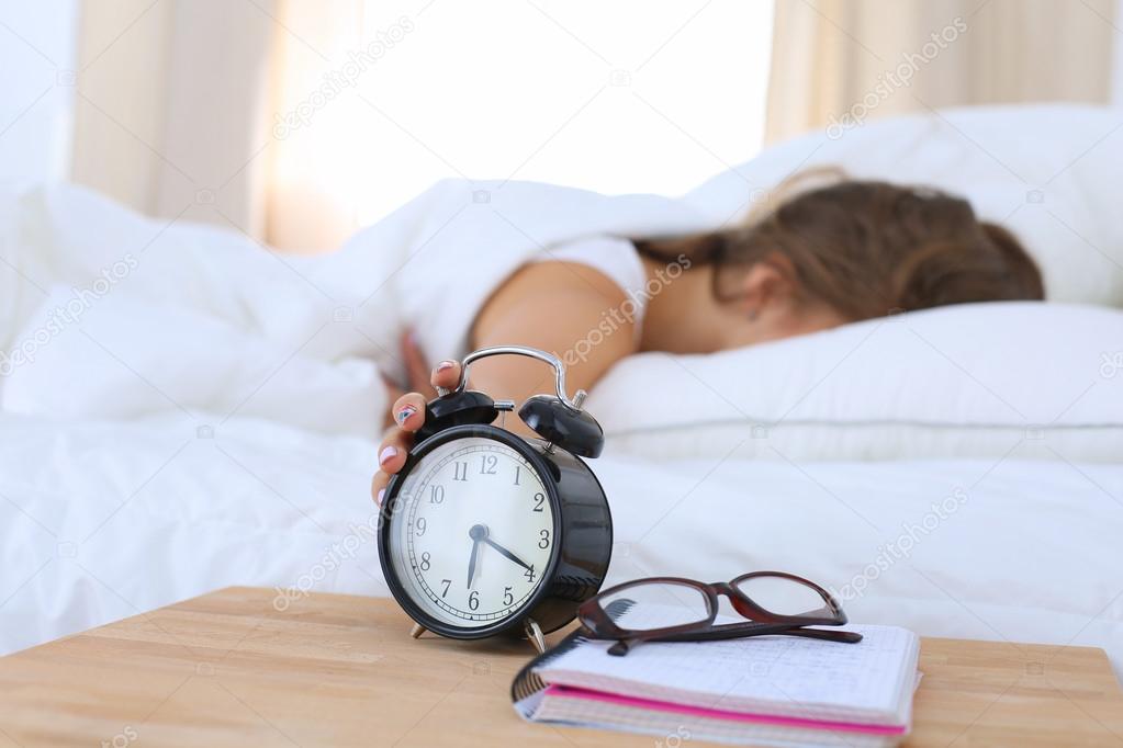 A young woman putting her alarm clock off in the morning