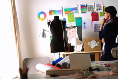 Güzel moda tasarımcısı stüdyoda duruyor.