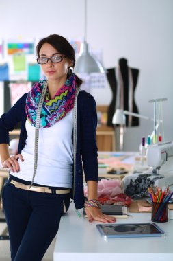 Güzel moda tasarımcısı stüdyoda duruyor.