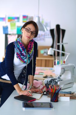 Güzel moda tasarımcısı stüdyoda duruyor.