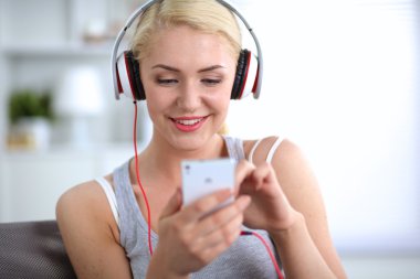 Evdeki genç ve güzel kadın kanepede oturup müzik dinliyor.