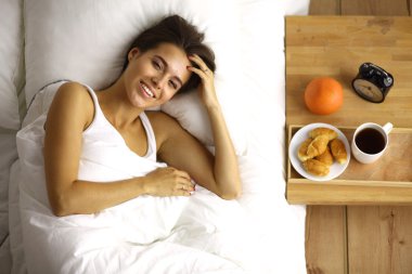 Genç ve güzel bir kadın yatakta yatıyor.