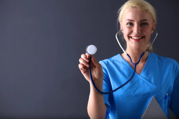 Medico femminile con uno stetoscopio in ascolto, isolato su sfondo grigio — Foto Stock