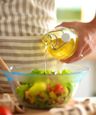 Masanın yanında duran taze salatayı karıştıran genç kadın.