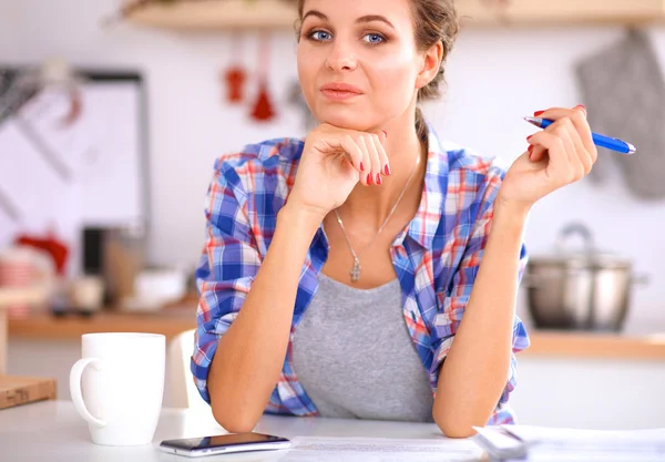 Glimlachende jonge vrouw in de keuken, geïsoleerd op kerst achtergrond — Stockfoto