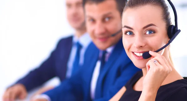 Retrato de mulher de negócios bonita em fones de ouvido sorrindo com colegas de fundo — Fotografia de Stock