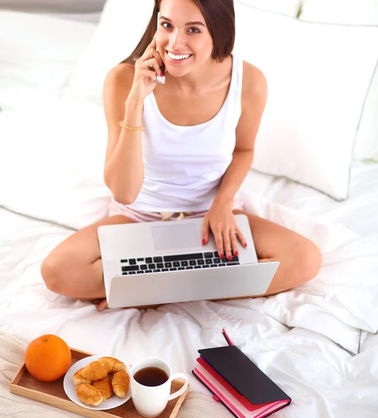 Young beautiful woman sitting in bed talking on the phone — Stock Photo, Image