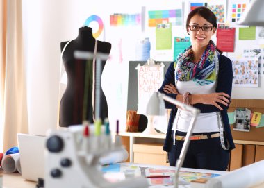 Güzel moda tasarımcısı stüdyoda duruyor.