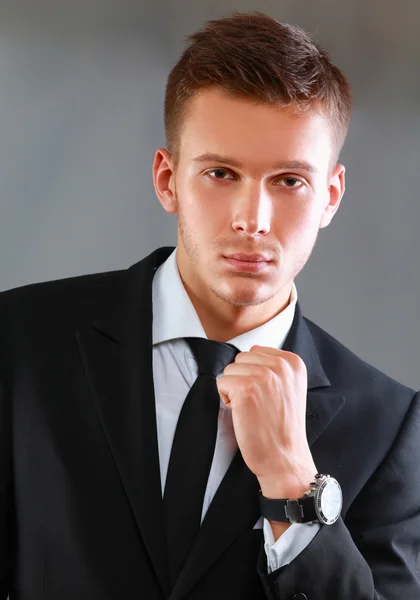 Portrét muže úspěšného podnikání mladých stojí izolované na šedém pozadí — Stock fotografie