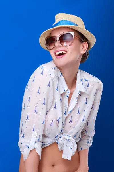 Giovane donna in cappello e occhiali da sole, isolata su sfondo blu — Foto Stock