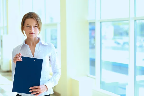 Business woman standing in foreground with a folder in her hands — Stock Photo, Image