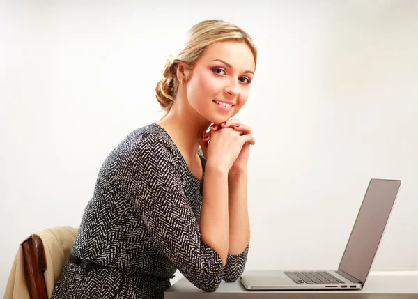 Ett porträtt av en affärskvinna som sitter vid ett skrivbord med en bärbar dator — Stockfoto