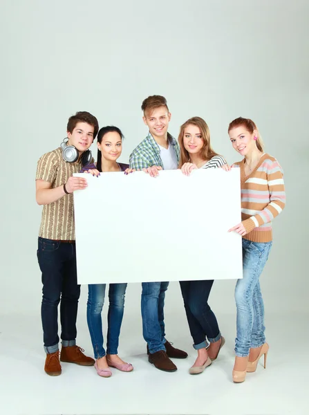 Grupo de jóvenes amigos sosteniendo un tablero en blanco, aislados sobre fondo blanco —  Fotos de Stock