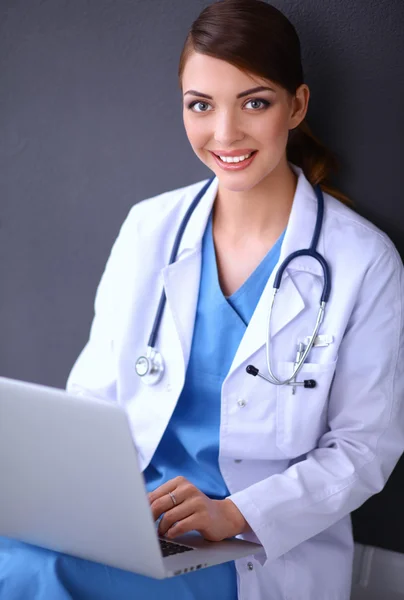 Femme médecin travaillant assis sur fond gris — Photo