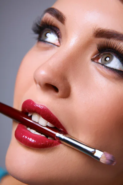 Womans lips holding make up brush — Stock Photo, Image