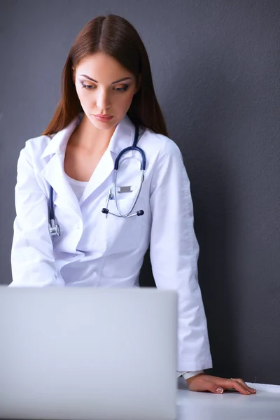 Médico femenino trabajando sentado sobre fondo gris — Foto de Stock