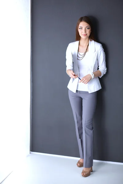 Young woman holding a laptop, standing on gray background — Stock Photo, Image