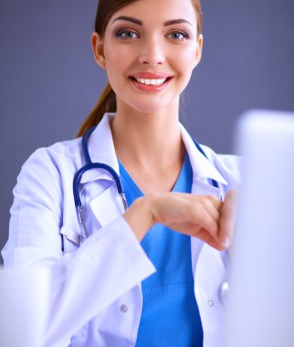 Gri arka planda oturan kadın doktor