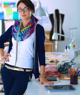 Güzel moda tasarımcısı stüdyoda duruyor.