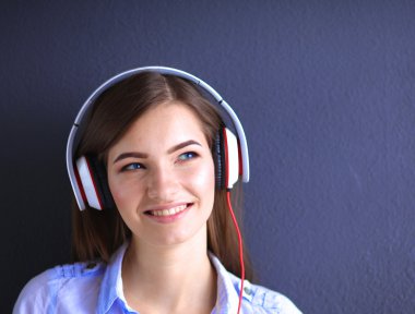 Duvara yakın katta oturan kulaklıklar ile gülümseyen kız