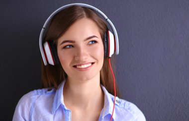 Duvara yakın katta oturan kulaklıklar ile gülümseyen kız