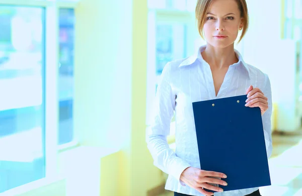 Business woman standing in foreground with a folder in her hands — Stock Photo, Image