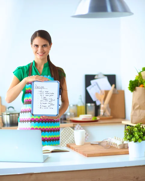 Femme dans la cuisine à la maison, debout près du bureau avec dossier — Photo