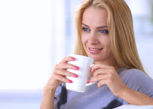 Joven hermosa mujer con una taza en el sofá en casa — Foto de Stock