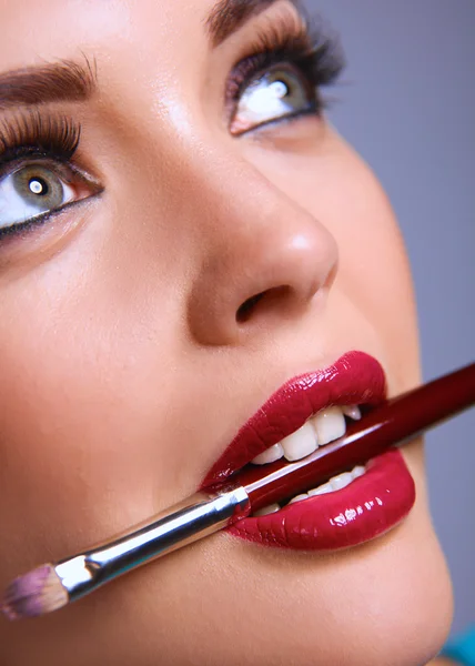 Womans lips holding make up brush — Stock Photo, Image