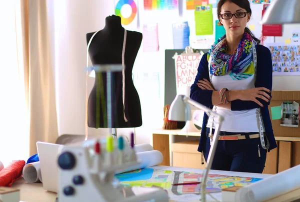 Güzel moda tasarımcısı stüdyoda duruyor.