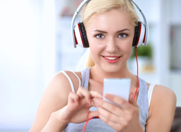 Young beautiful woman at home sitting on sofa and listening music — Stock Photo, Image