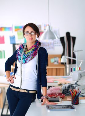 Güzel moda tasarımcısı stüdyoda duruyor.