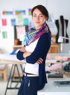 Güzel moda tasarımcısı stüdyoda duruyor.