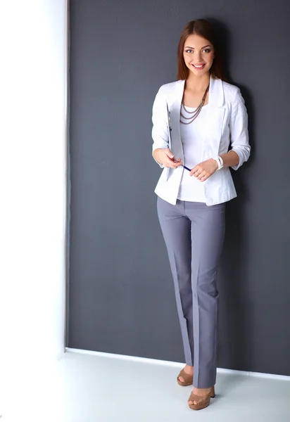 Young woman holding a laptop, standing on gray background — Stock Photo, Image