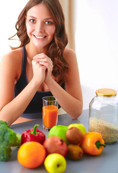 Chica sentada en la cocina en el escritorio con frutas y vasos con jugo — Foto de Stock