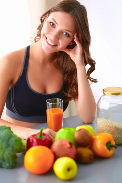 Fille assise dans la cuisine sur le bureau avec des fruits et des verres avec du jus — Photo