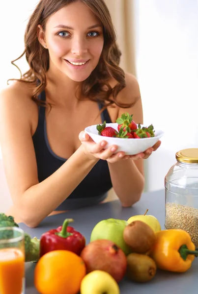 Chica sentada en la cocina en el escritorio con frutas y vasos con jugo — Foto de Stock