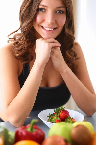 Fille assise dans la cuisine sur le bureau avec des fruits et des verres avec du jus — Photo