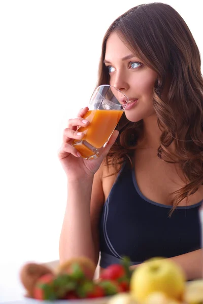 Flicka sitter i köket på skrivbord med frukt och glas med juice — Stockfoto