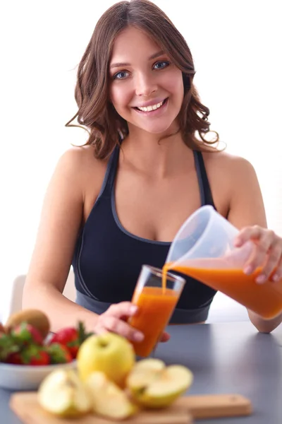 Flicka sitter i köket på skrivbord med frukt och glas med juice — Stockfoto