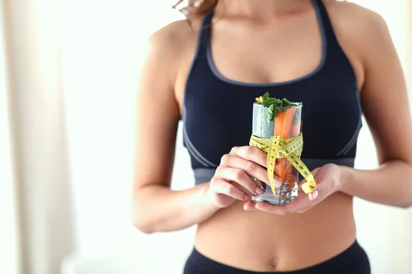 Donna che tiene un bicchiere pieno di macedonia di frutta fresca con un metro a nastro intorno al bicchiere — Foto Stock