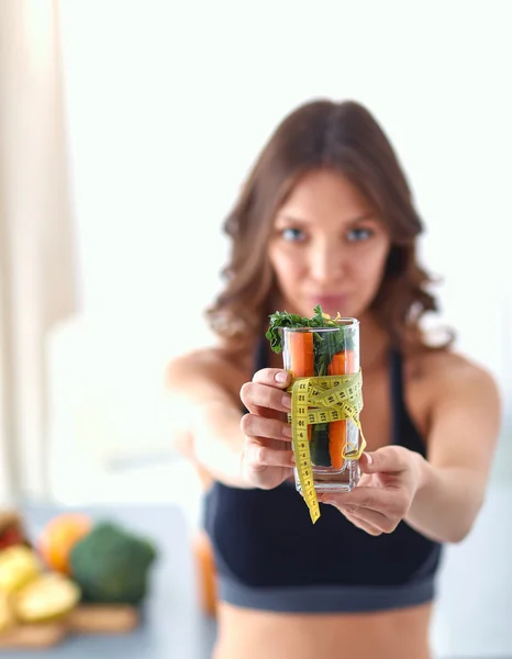 Kvinna som håller ett dricksglas fullt av färsk fruktsallad med ett måttband runt glaset — Stockfoto
