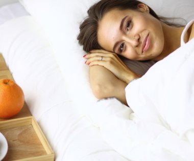 Genç ve güzel bir kadın yatakta yatıyor.