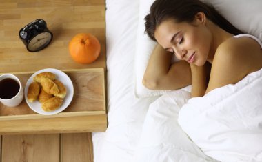 Genç ve güzel bir kadın yatakta yatıyor.