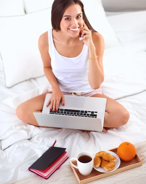 Młoda piękna kobieta siedzi na łóżku rozmawia przez telefon — Zdjęcie stockowe
