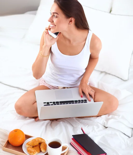 Jonge mooie vrouw zitten in bed praten over de telefoon — Stockfoto