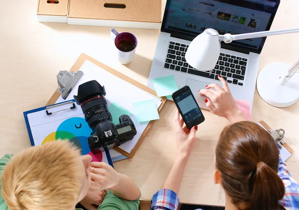 Vrouwelijke fotograaf zittend op het bureau met laptop — Stockfoto