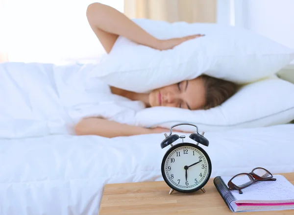 Una mujer joven apagando su despertador por la mañana — Foto de Stock