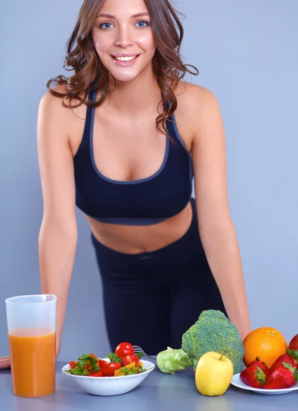 Mulher jovem e bonita de pé perto da mesa com legumes — Fotografia de Stock