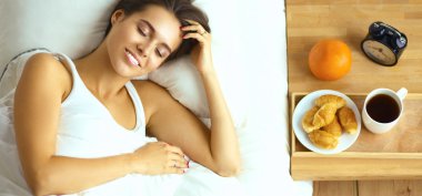 Genç ve güzel bir kadın yatakta yatıyor.